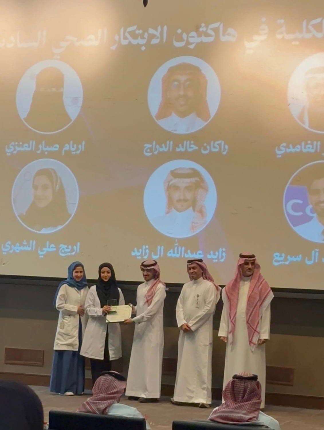 زايد آل زايد على المسرح يستلم شهادة تكريم في جامعة الملك سعود بن عبدالعزيز للعلوم الصحية.